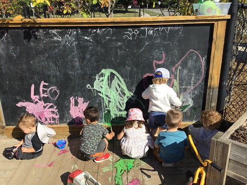 Children in front of a large chalk board outside