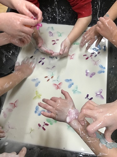 Children's hands exploring oobleck in the sensory bin