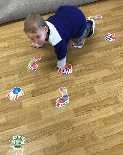 A child crawling along the path of stickers on the floor