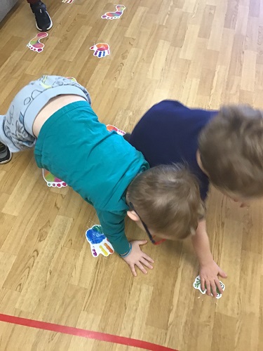Two children crawling across the floor following a picture path