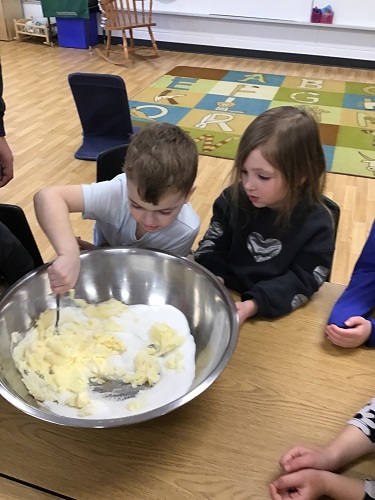 Children taking turns mixing and adding ingredients in a large bowl