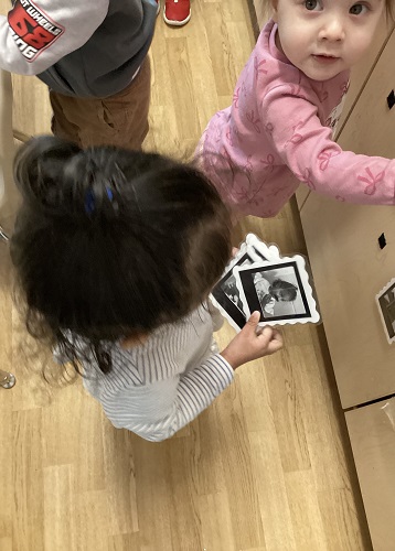 A child holding photographs of her peers and looking at them