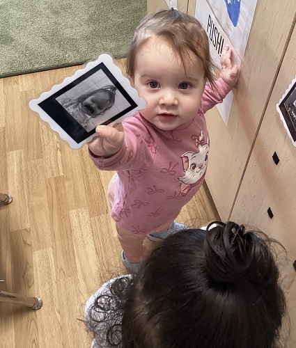 A child holding a photo of herself out to show her off
