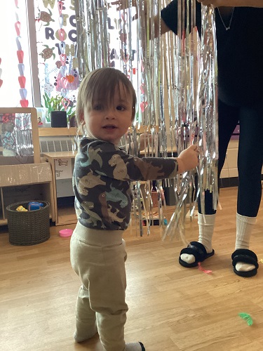 A child standing and holding onto the hanging tinsel