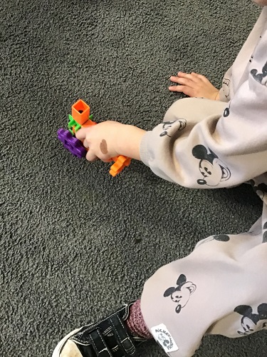 A child's hands pushing a vacuum they created out of gears