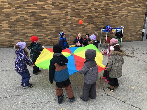Children in a circle holding a parachute