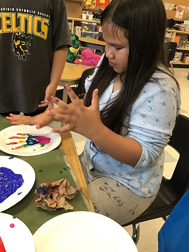 A child painting handprints at a table