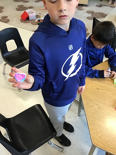 A child holding up a clay heart that he made