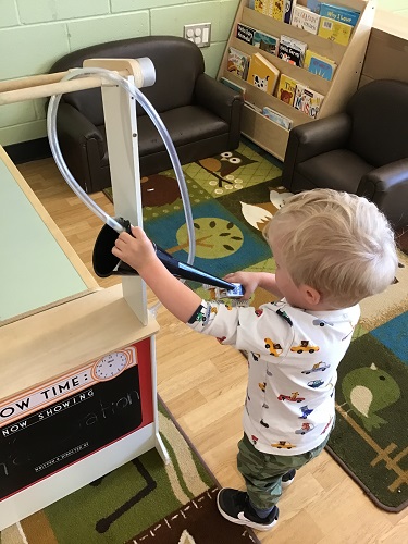 A child using the gas station to fill up his small toy car