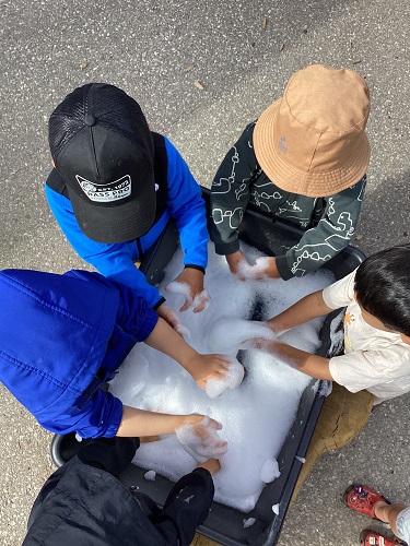 Children standing around a bin full of bubbles and foam!