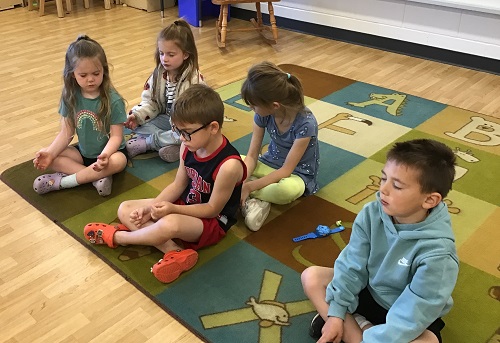 Children sitting on a carpet doing a guided mediation
