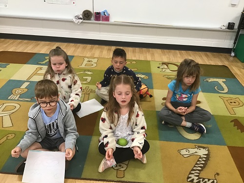 Children sitting on a carpet doing a guided mediation
