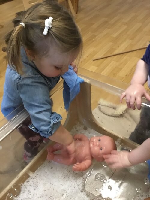 girl washing a baby doll