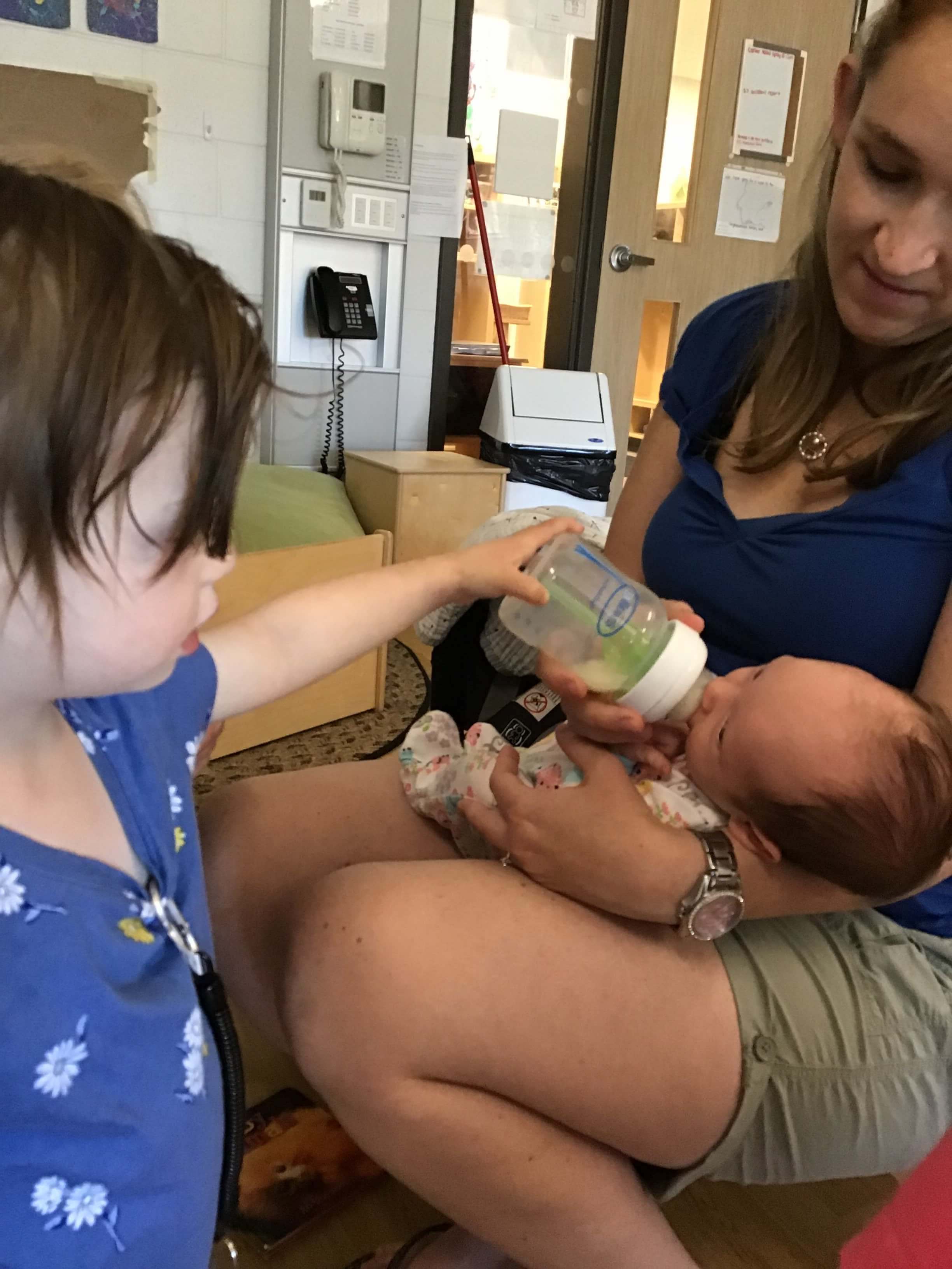 toddler feeding a baby her bottle