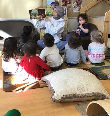 7 Toddler's sittingaround an educator who is reading a story
