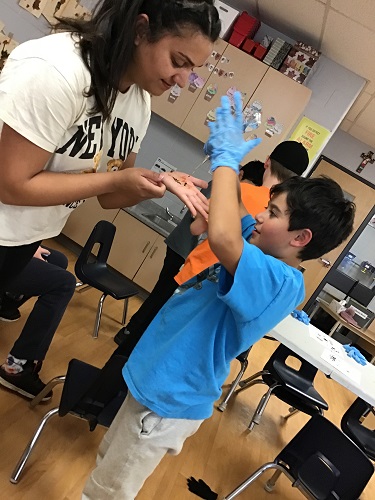 A school aged child applying Henna to the educators hand