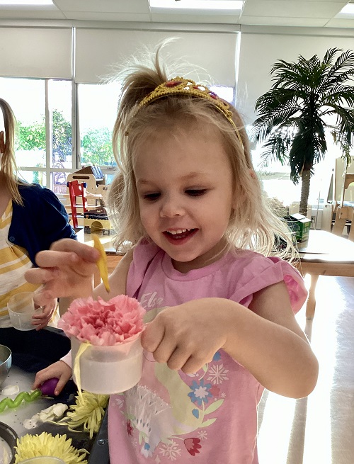 A preschool child holding a cup with sensory materials
