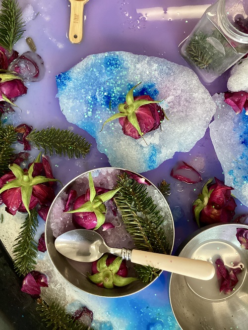 A display of a child's creation in the tuff tray with snow, ice, flowers and pine needles
