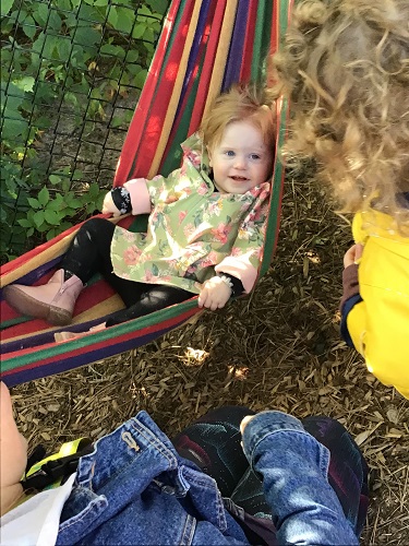 An infant is sitting in a hammock.