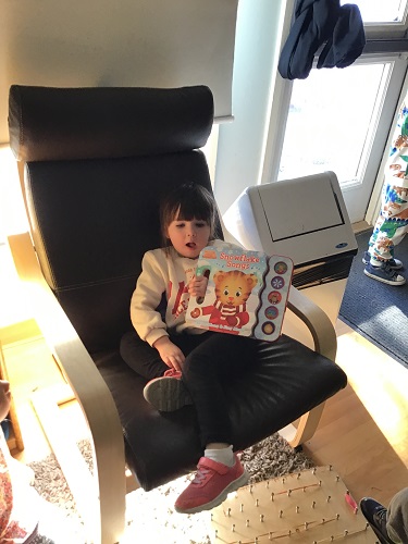 A preschooler is showing her classmates the book she brought today and had in their cubbie.