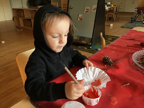 A preschooler is painting a coffee filter.