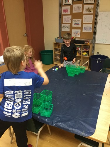 School-age children playing the pompom toss game