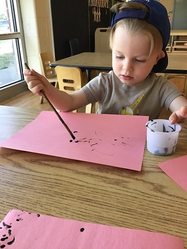 Toddler boy painting with a stick