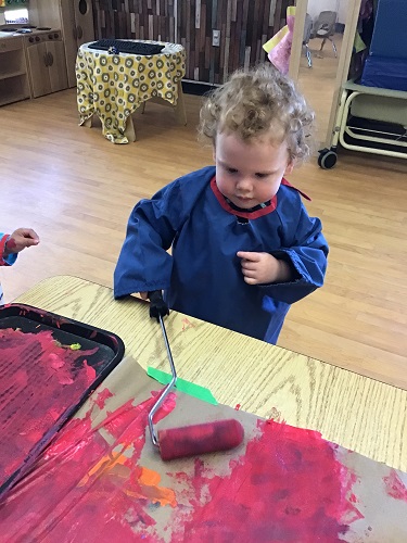 Toddler rolling paint on banner