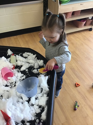 Toddler playing with snow in tuff tray