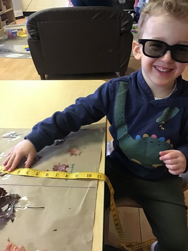 Preschool boy measuring leaf with measuring tape 