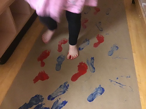 Child walking across paper with paint on feet