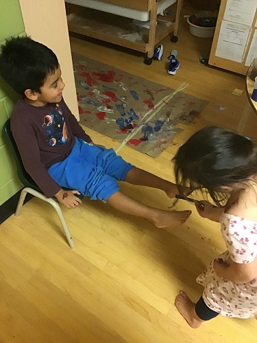 Child painting peers feet for activity 