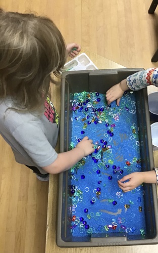 Kindergarten girl exploring the sand sensory bin