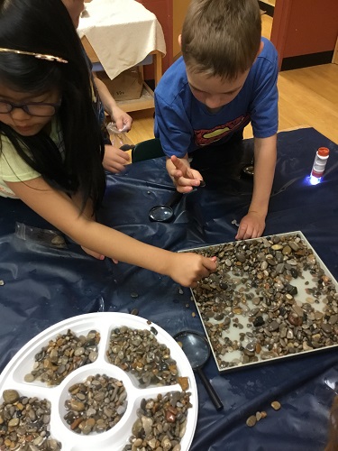 2 school-age children looking through rocks