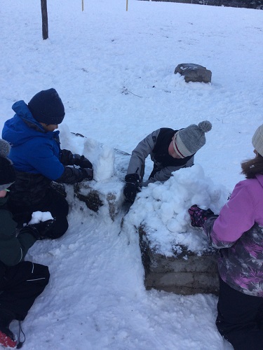 School-age children building with snow