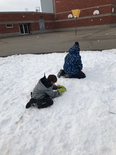 2 school-age boys gathering snow for building