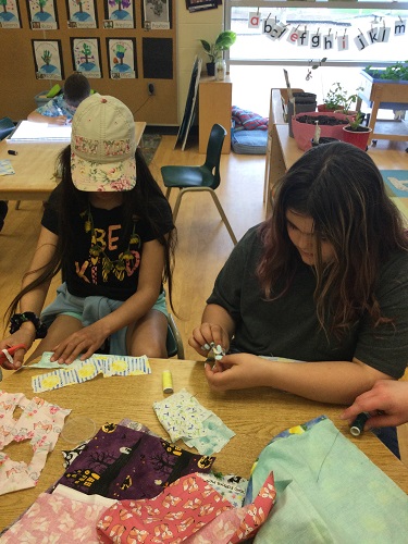 2 school age girls learning to thread a needle