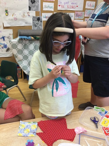 school age girl making doll dress