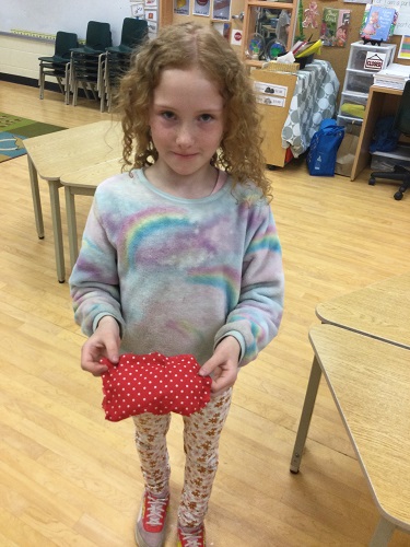 school age girl displaying the pillow she made 