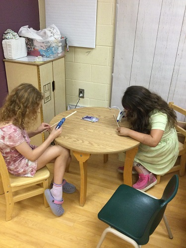 2 School-age girls creating their wands with hot glue guns