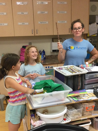 Educator holding up child's wand while child laughs