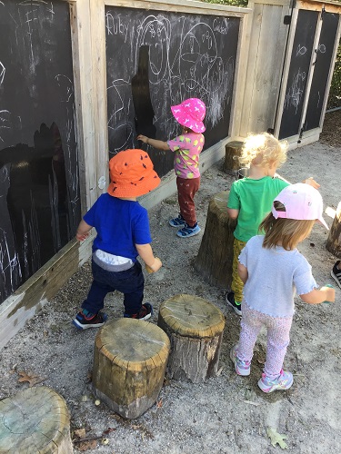 Toddlers cleaning chalk board with water 