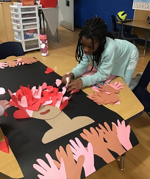 A school age child working on a poster highlighting Black History Month
