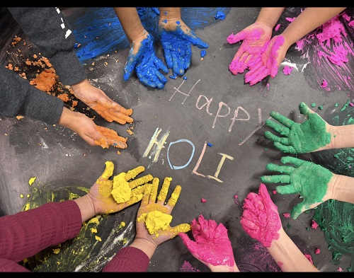 Children's hands holding colourful creations with the writing happy Holi