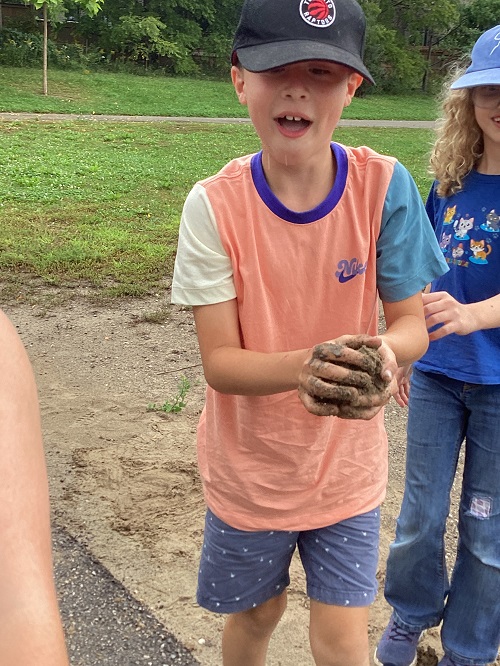 A school age child holding mud