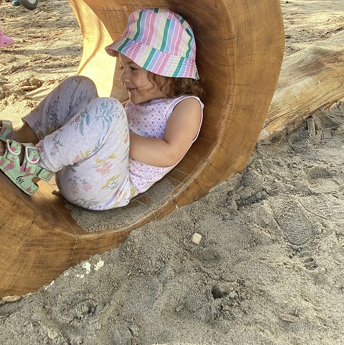 A toddler child exploring the playground tunnel