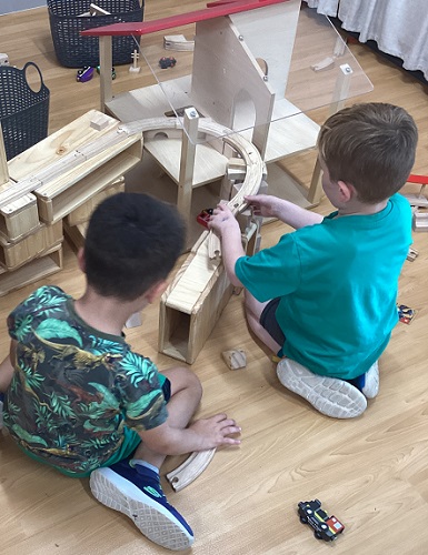 Two children build wiht blocks and train tracks