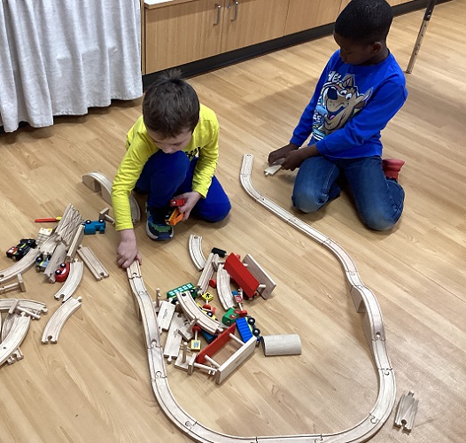 Two children build a train track