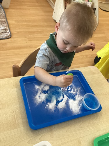 A child uses an eyedropper to mix materials