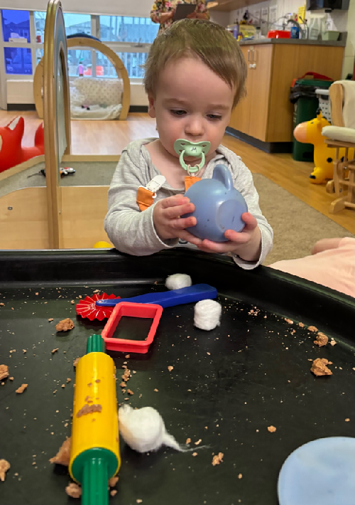 A child engaging with items in the tuff-tray.